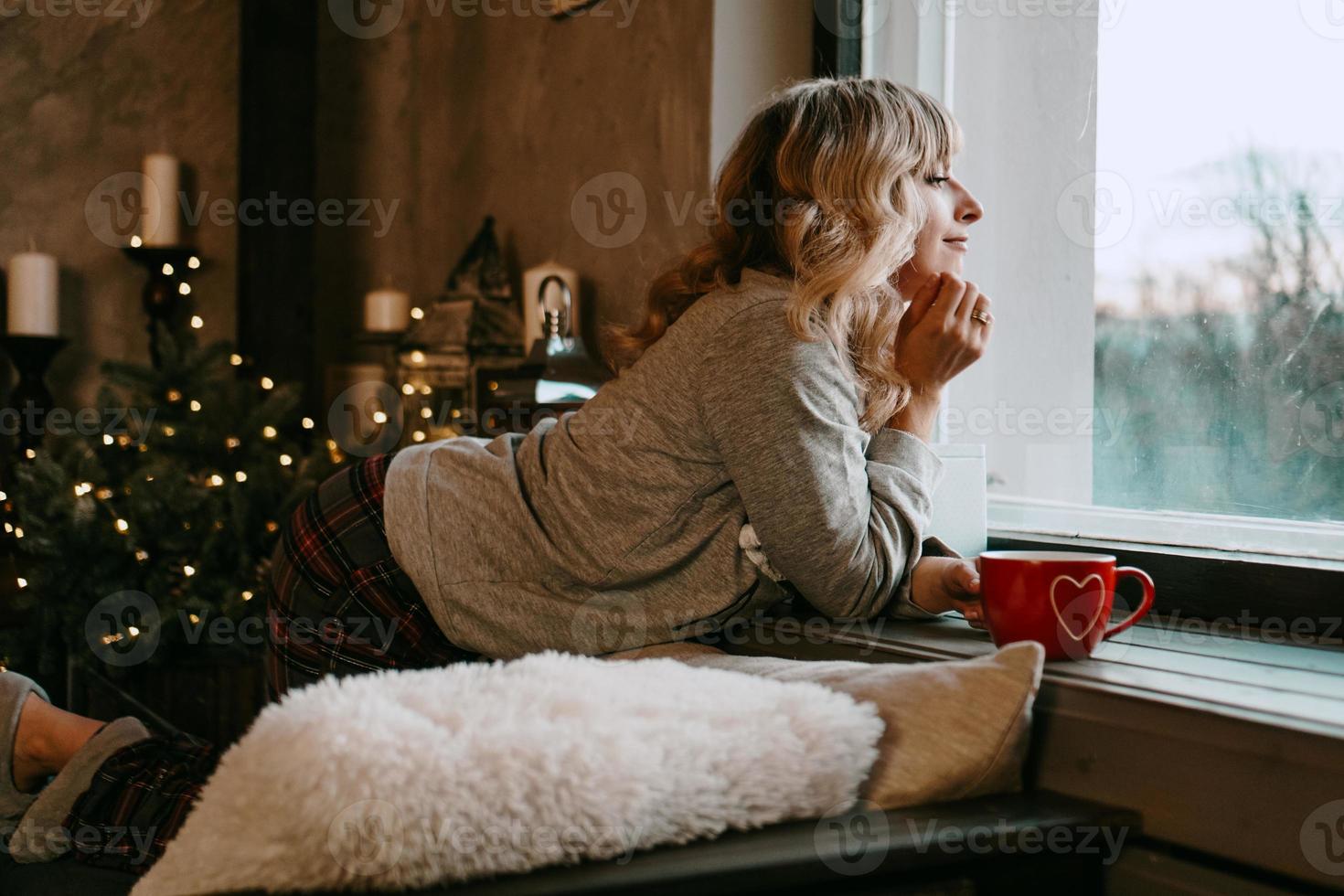 giovane donna con una tazza di tè in interni accoglienti di natale foto