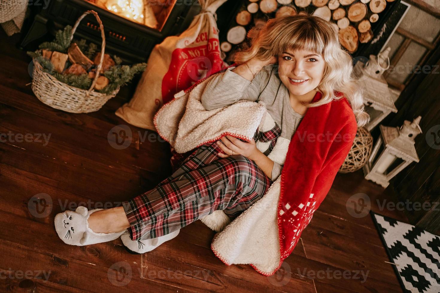 una bella giovane donna in un plaid rosso si siede nell'interno del nuovo anno foto