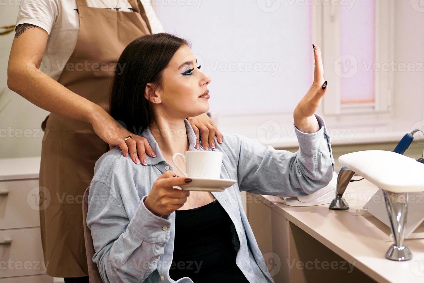 la ragazza guarda la sua manicure durante il massaggio nel salone di bellezza foto