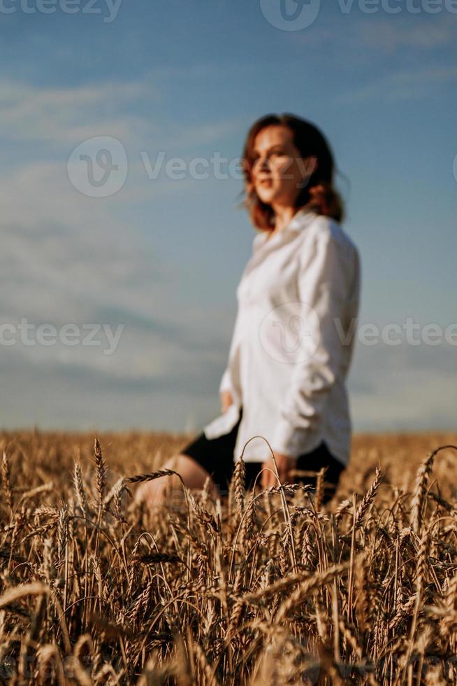 felice giovane donna in una camicia bianca in un campo di grano. giorno soleggiato. foto