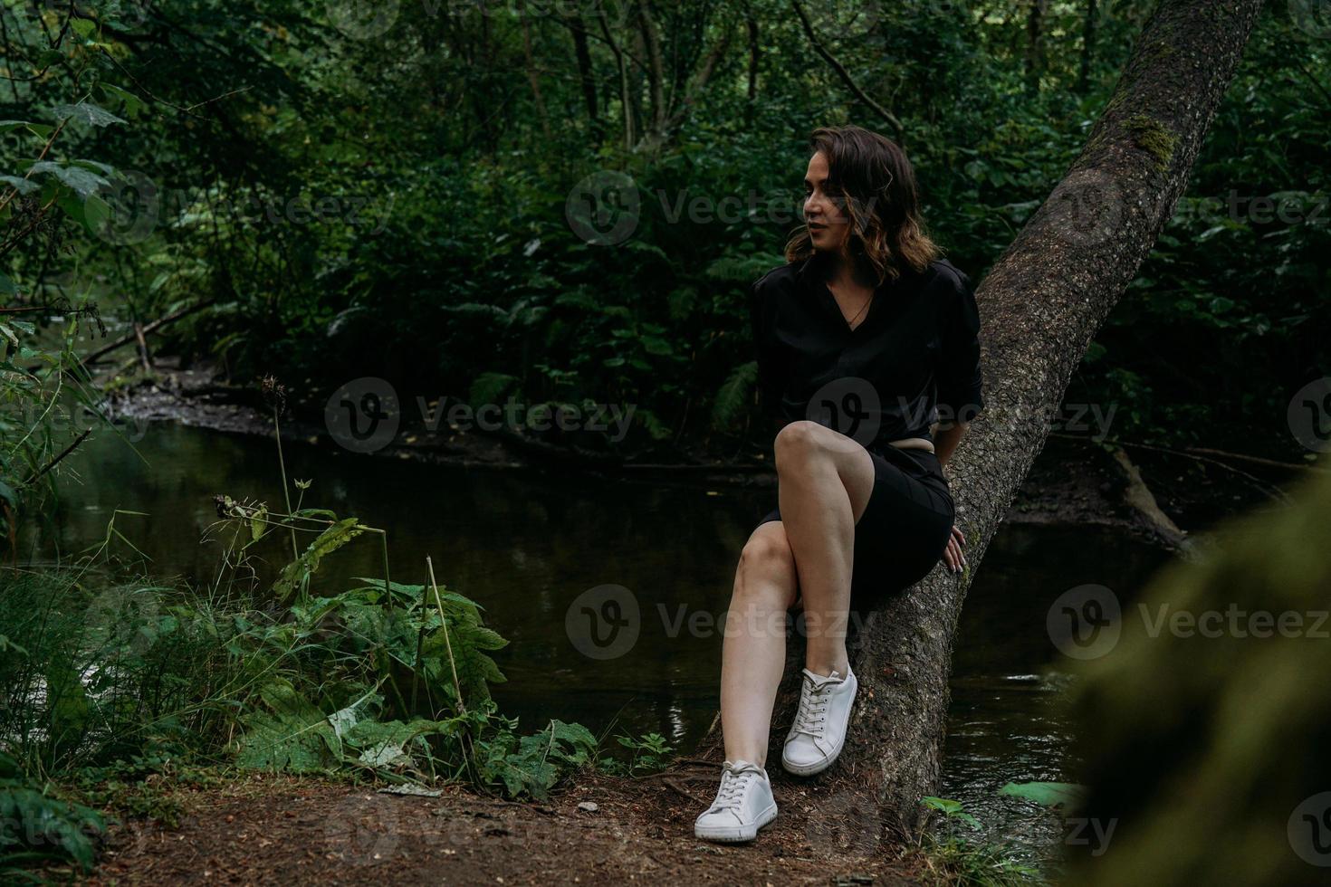 donna in abiti neri in un oscuro bosco di conifere. monitoraggio e viaggio foto