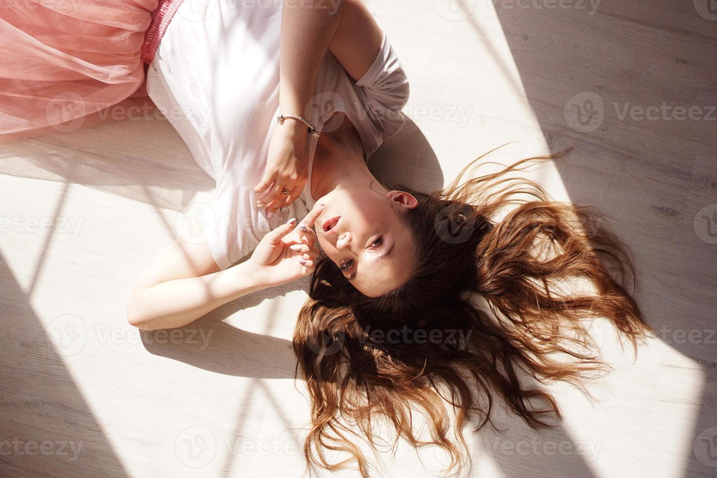 giovane donna, bella luce del sole. lei giace su un pavimento di legno foto