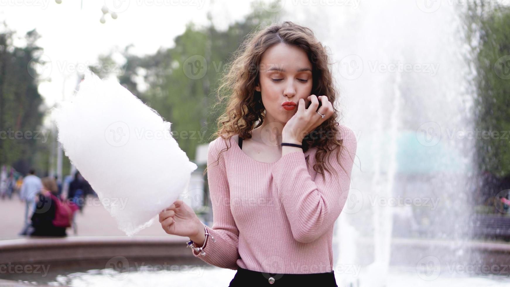 sorridente ragazza eccitata che tiene zucchero filato al parco divertimenti? foto