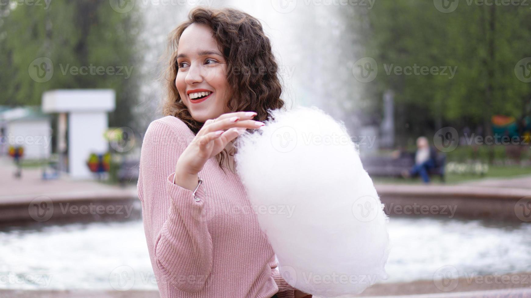 sorridente ragazza eccitata che tiene zucchero filato al parco divertimenti? foto