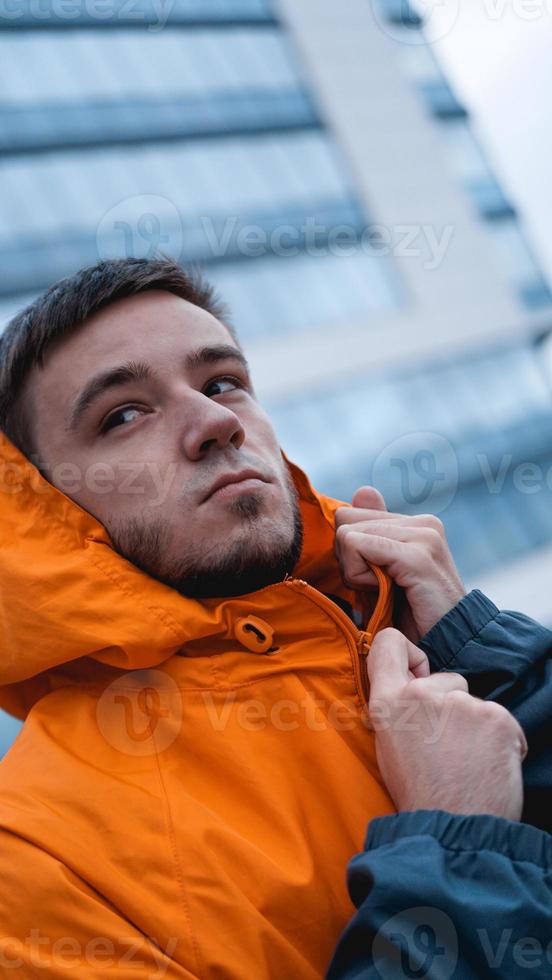 giovane uomo in divisa da lavoro arancione - edificio in vetro sullo sfondo foto