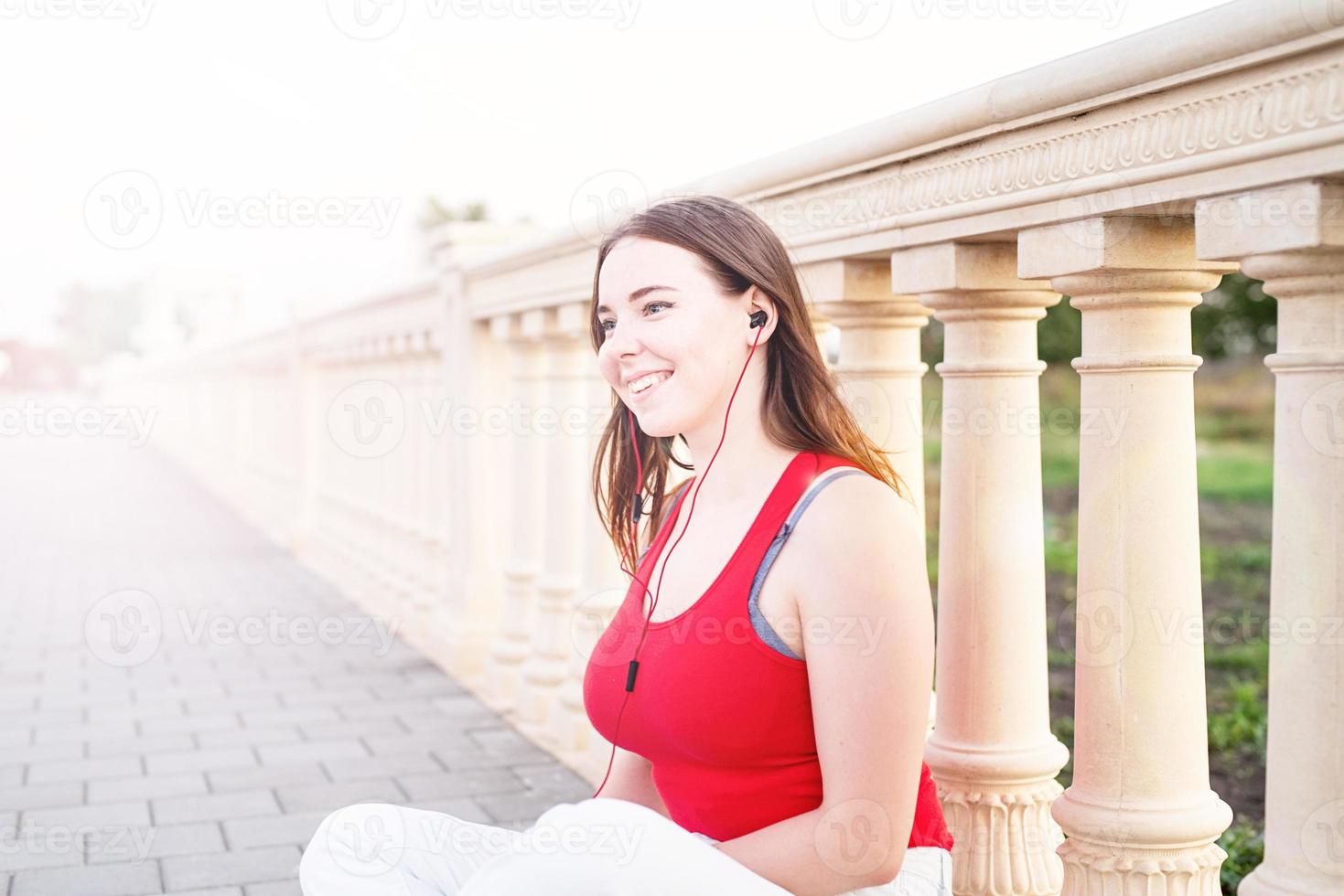 ragazza seduta accanto alla recinzione della colonna che ascolta la musica foto