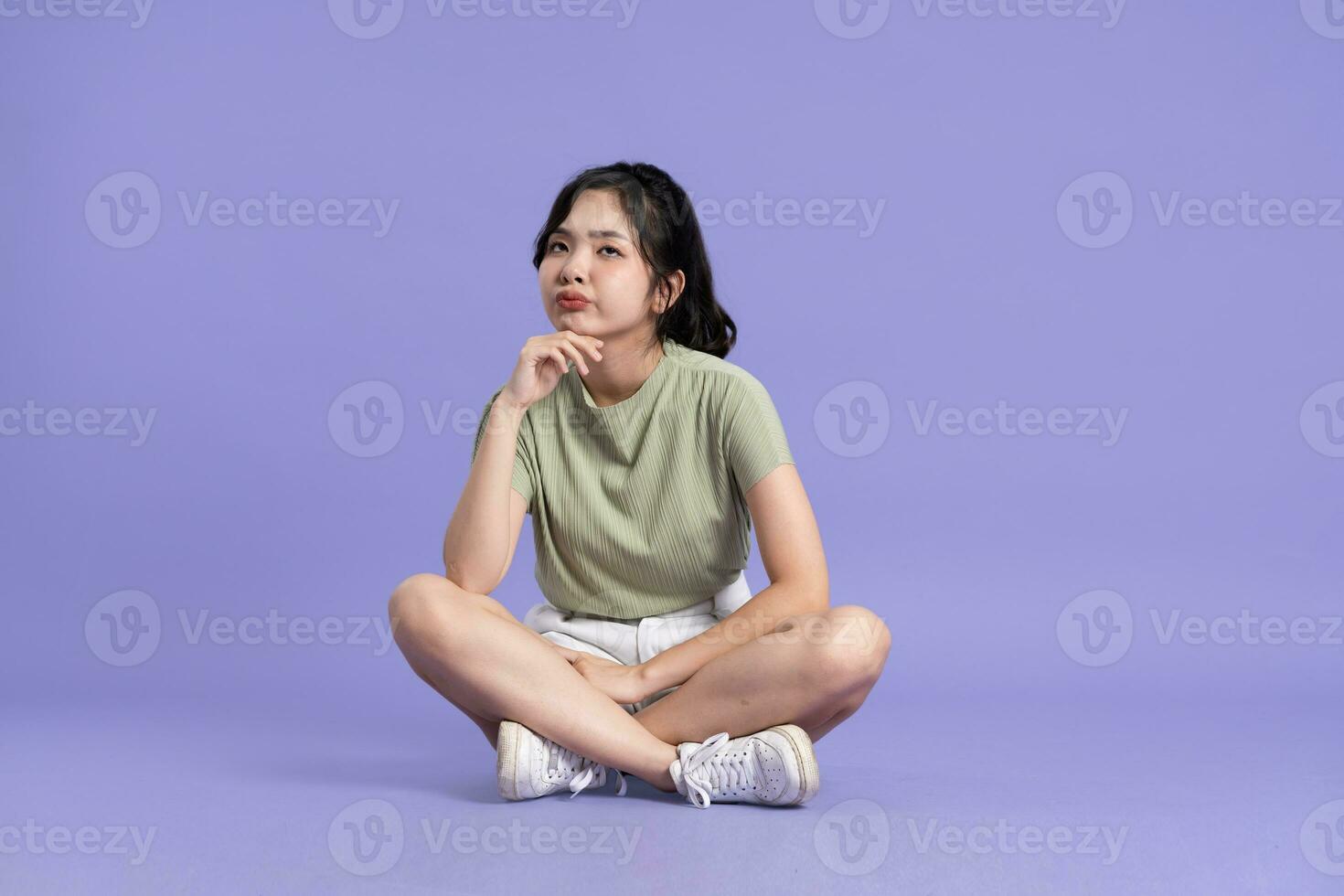 ritratto di bellissimo asiatico ragazza seduta su viola sfondo foto