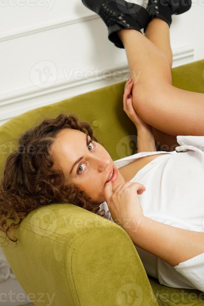 giovane bella modella con le gambe lunghe sul divano verde. donna sexy a casa foto