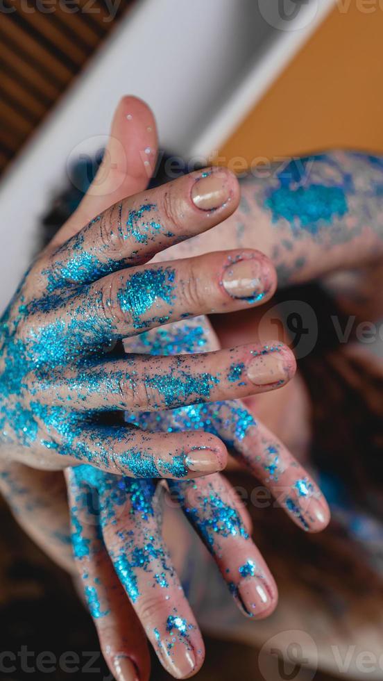 glitter blu sulle mani della donna. movimenti fluidi delle mani foto