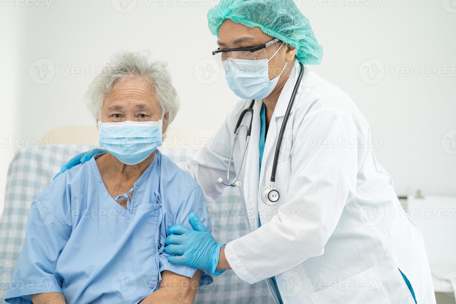il medico aiuta il paziente anziano asiatico che indossa la maschera per proteggere il coronavirus foto