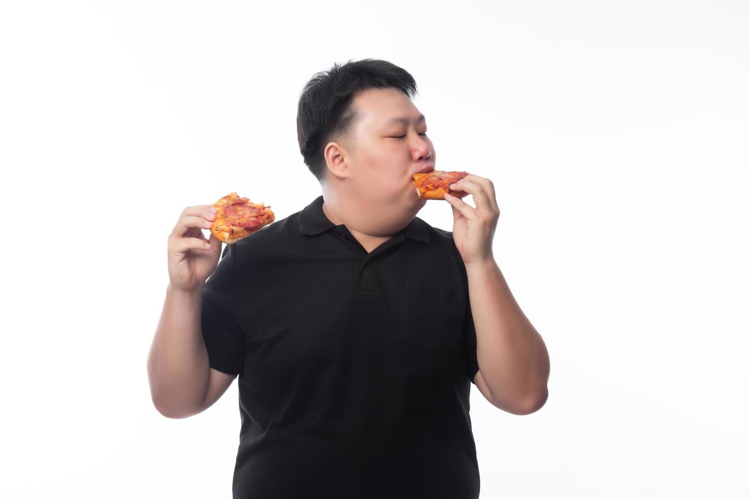 giovane uomo asiatico grasso divertente che mangia pizza hawaiana e formaggio? foto