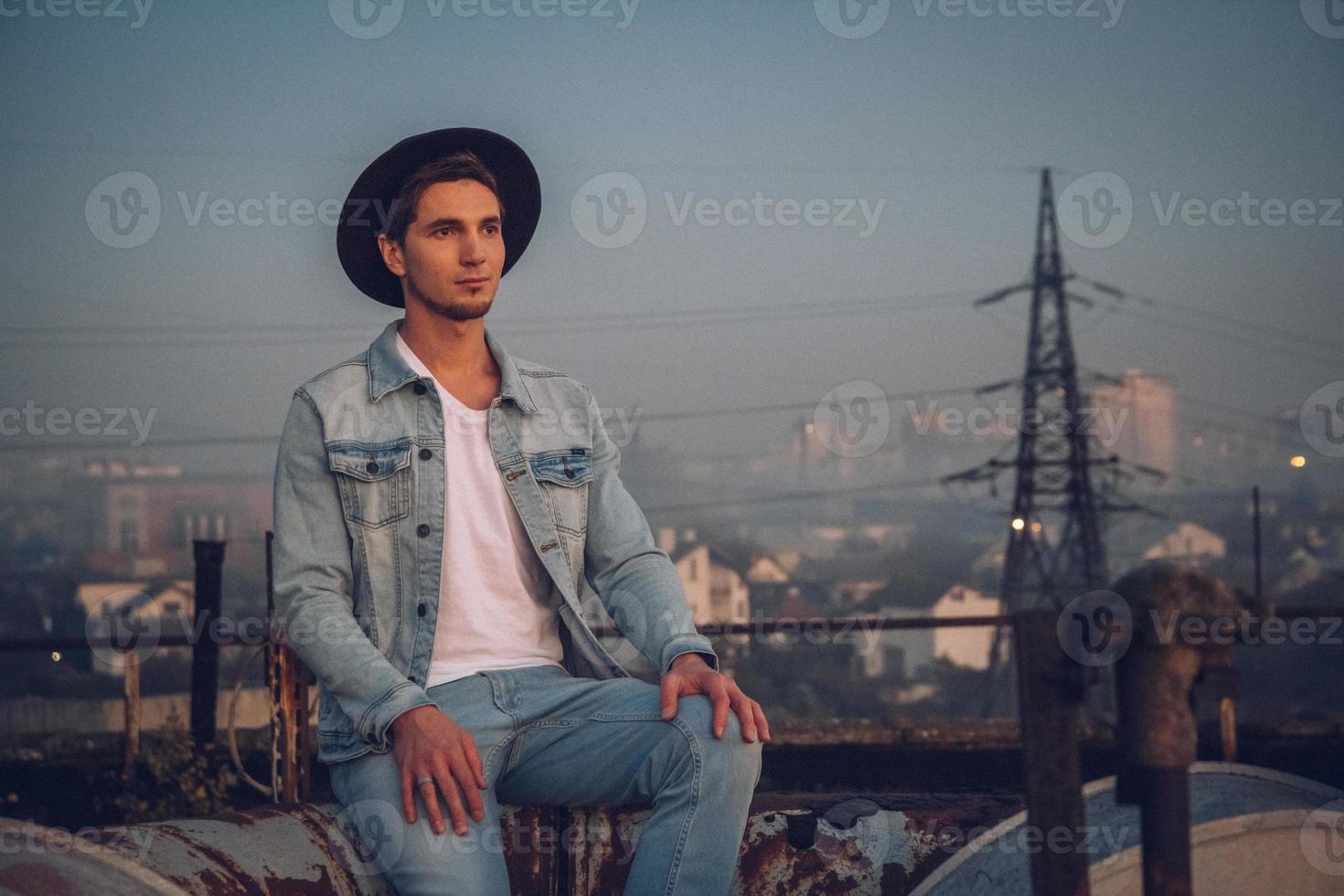 uomo con cappello che indossa camicia bianca e jeans sullo sfondo della città foto