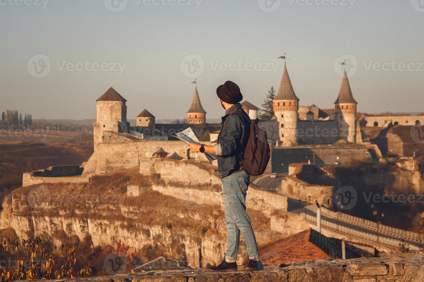 uomo davanti a un vecchio castello con una mappa foto