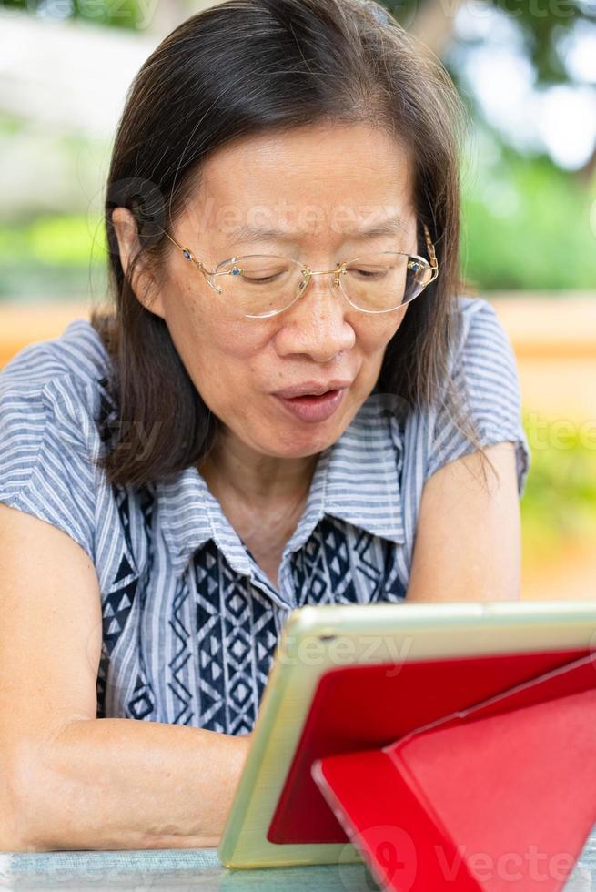 donna matura che usa la tavoletta digitale a casa foto