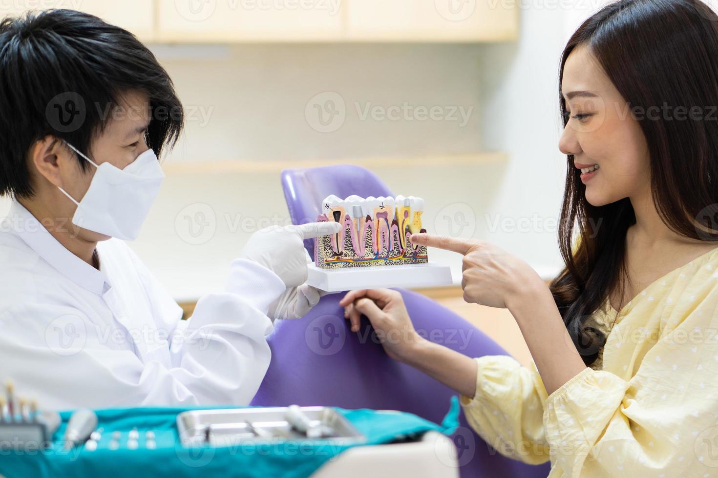 dentista che insegna al paziente l'igiene dei denti in clinica foto