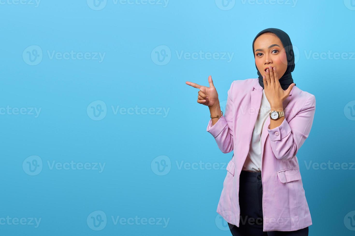 donna asiatica sorpresa che indica le dita nello spazio vuoto foto