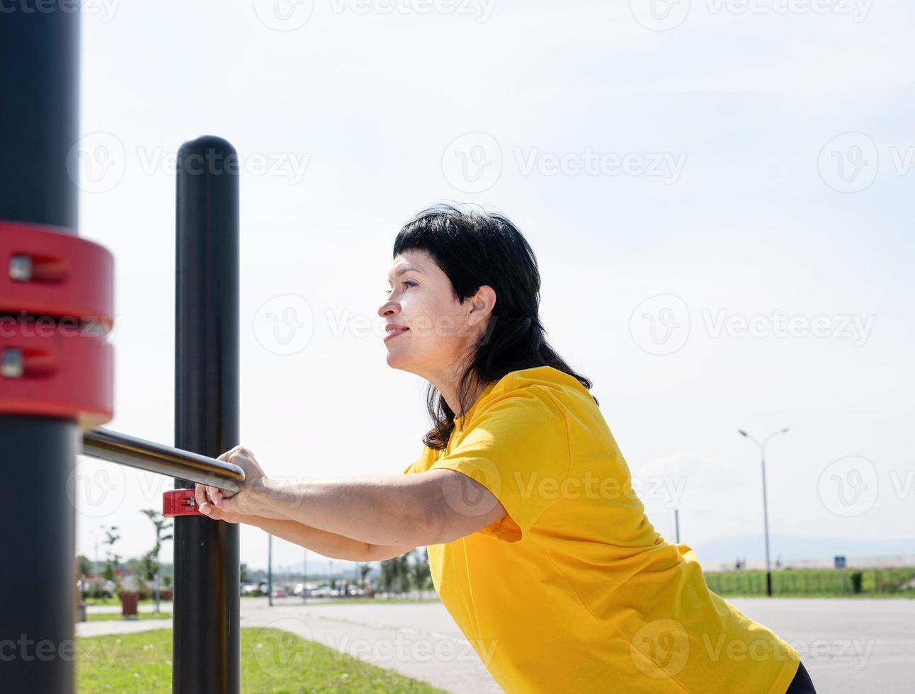 donna sorridente che fa flessioni all'aperto sul campo sportivo foto