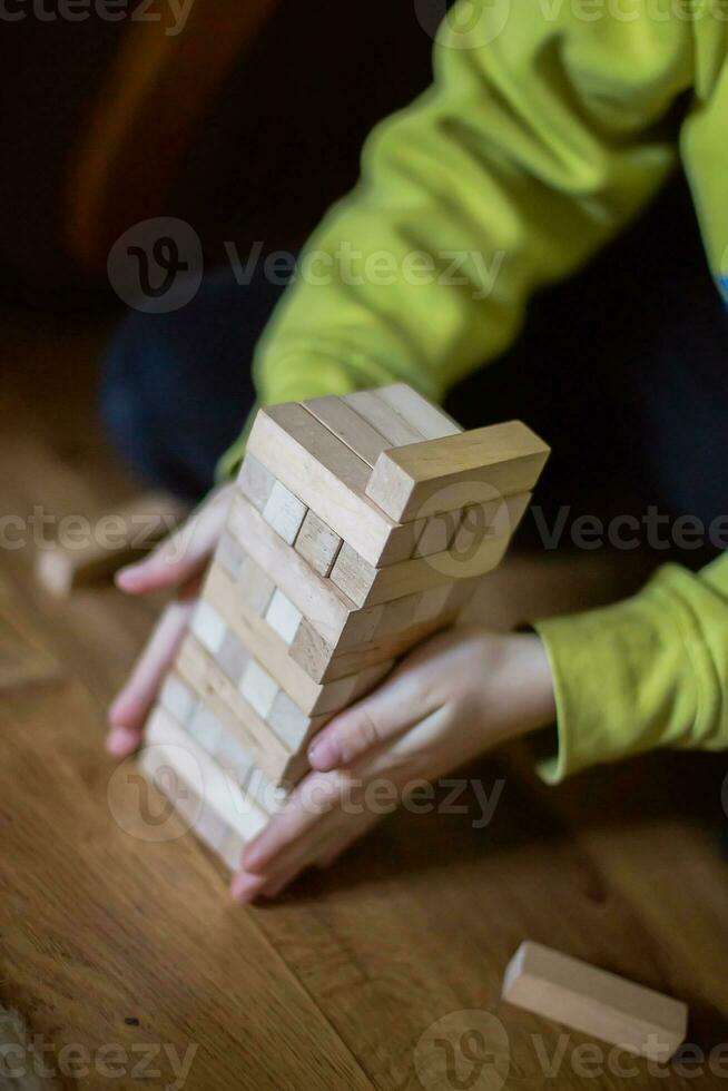 il bambino costruisce un' Torre di di legno blocchi. morbido messa a fuoco foto