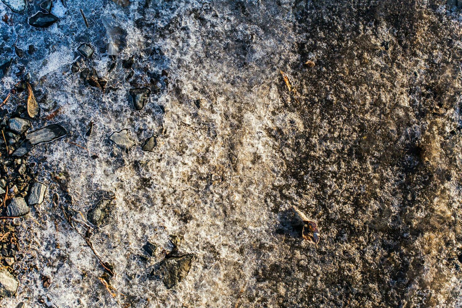 neve copertina e ghiaccio su il congelato terra con pietre e sabbia. sn foto