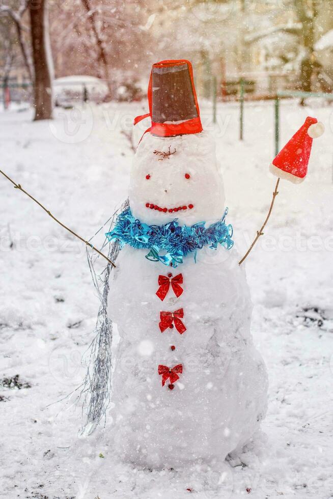 contento pupazzo di neve con Sorridi contro il fondale di inverno paesaggio durante nevicata foto