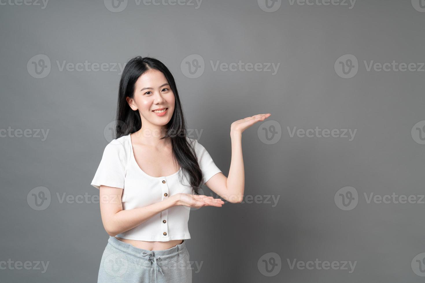 donna asiatica con la faccia sorridente e la mano che si presenta sul lato foto