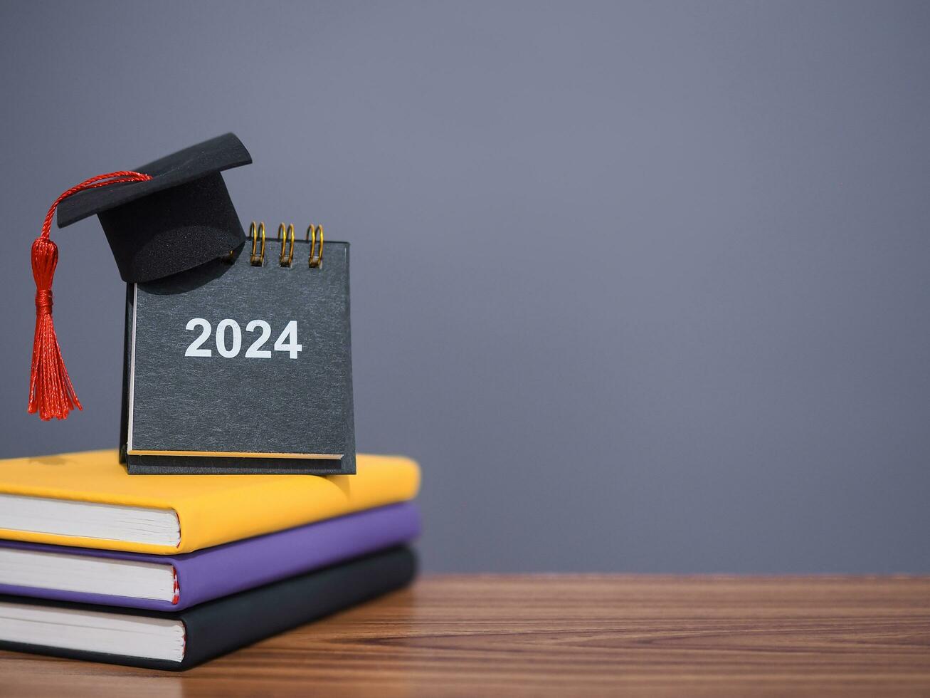 studia obiettivi, 2024 scrivania calendario con la laurea cappello su colorato rilegato libro. il concetto per risoluzione, obiettivo, azione, pianificazione, e gestire tempo per successo diplomato nel nuovo anno 2024 foto