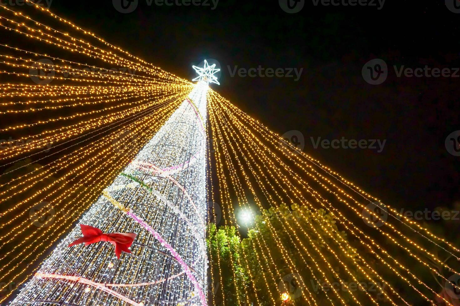 Guarda su Visualizza sfocato e bokeh di Natale albero illuminazione su notte tempo sfondo. foto