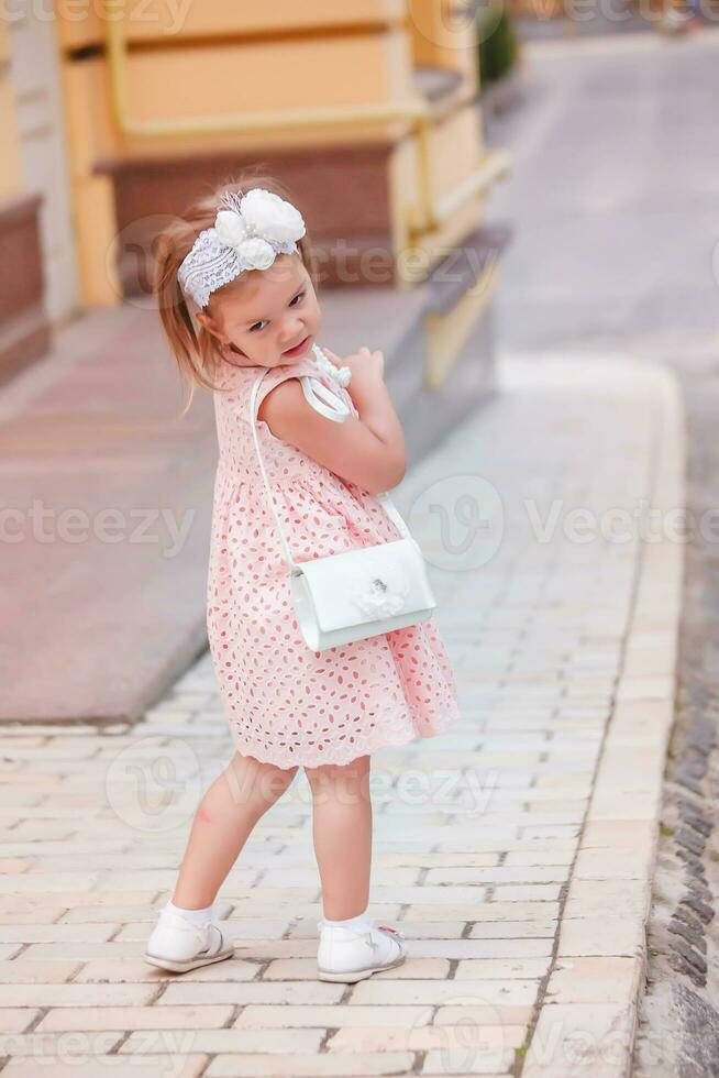 bellissimo ragazza nel un' rosa vestito con Borsa su le spalle trasformato e guardato dietro a lui. Hild cerca un' nuovo vestire. foto