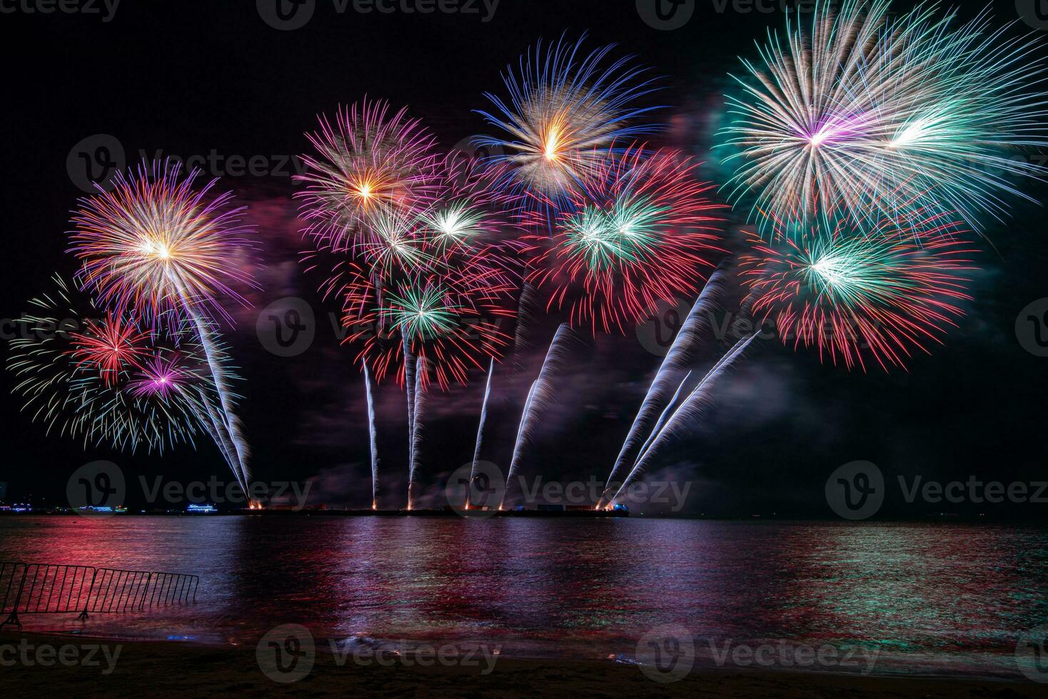incredibile bellissimo spettacolo pirotecnico colorato nella notte di celebrazione, che mostra sulla spiaggia del mare con multi colore di riflessione sull'acqua foto