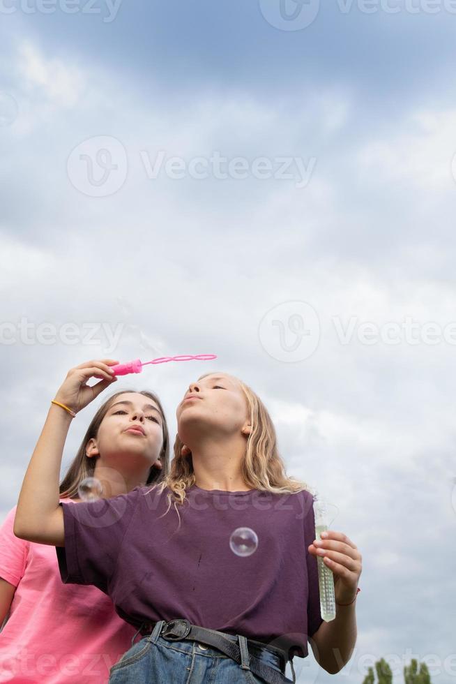 due amiche che soffiano bolle di sapone - spensierate e divertenti foto