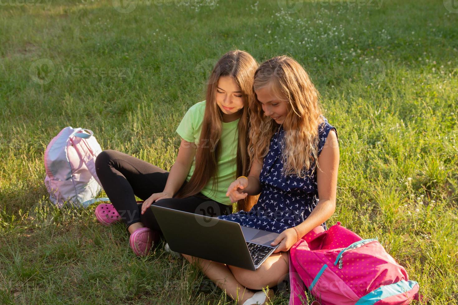 due ragazze con laptop sull'erba fuori foto
