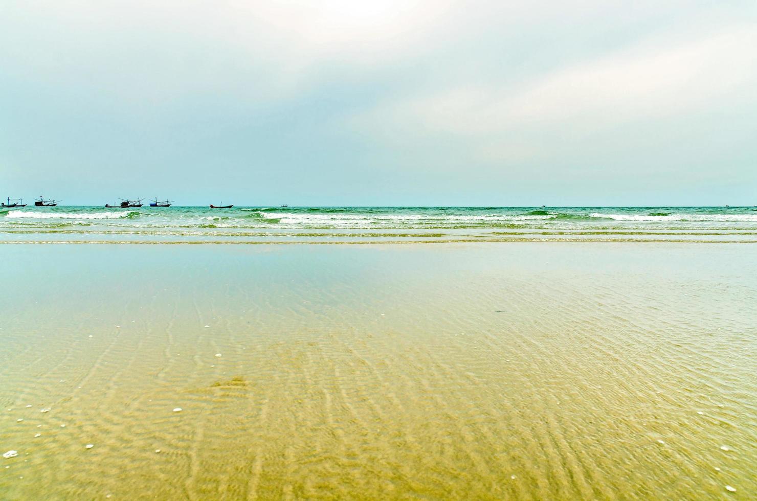 la vista della spiaggia di sabbia e dell'onda del mare con roccia e barriera corallina la mattina? foto