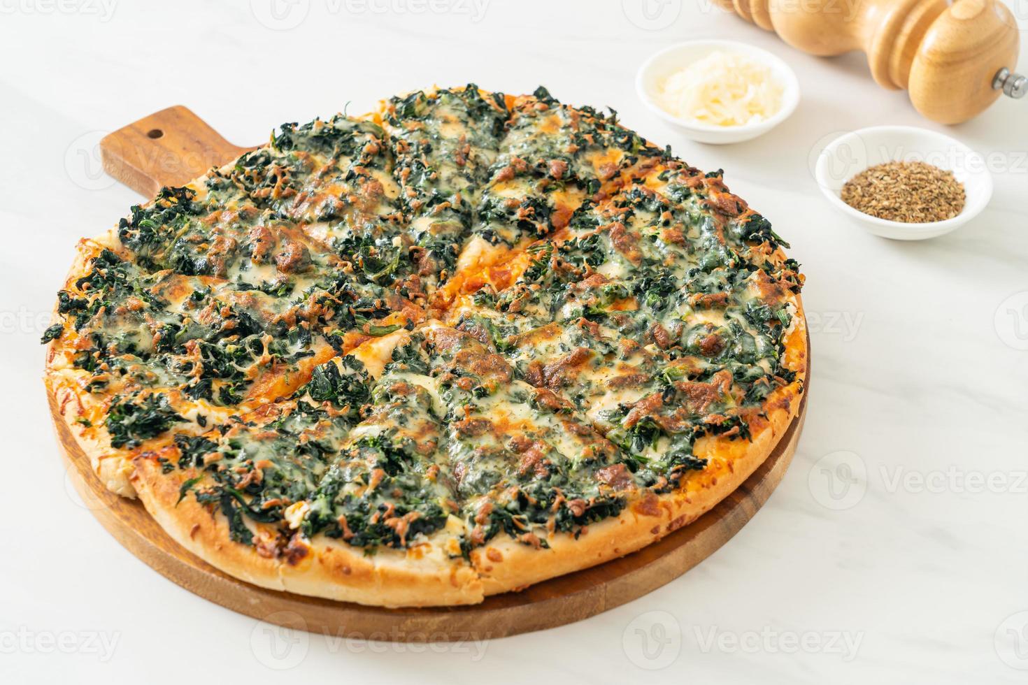 pizza spinaci e formaggio su teglia di legno foto