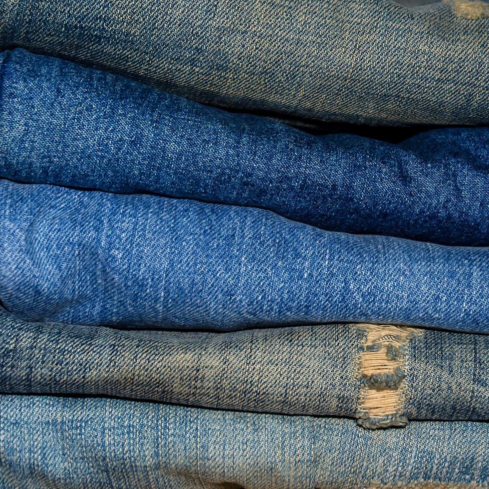 i jeans blu e i jeans mancano di consistenza sul tavolo, i jeans si sovrappongono. foto