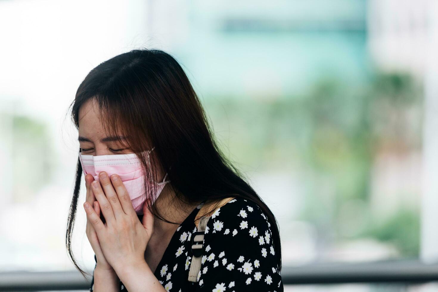 giovane asiatico donna indossare maschera e starnuti nel il strada foto