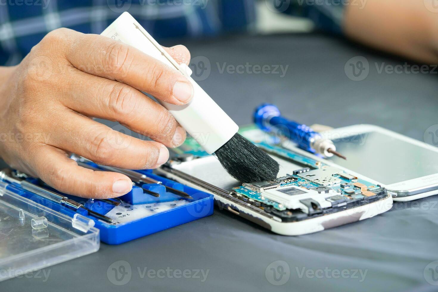 asiatico tecnico riparazione e pulizia sporco micro circuito principale tavola di smartphone elettronico tecnologia con spazzola, hardware, mobile Telefono, aggiornare concetto. foto