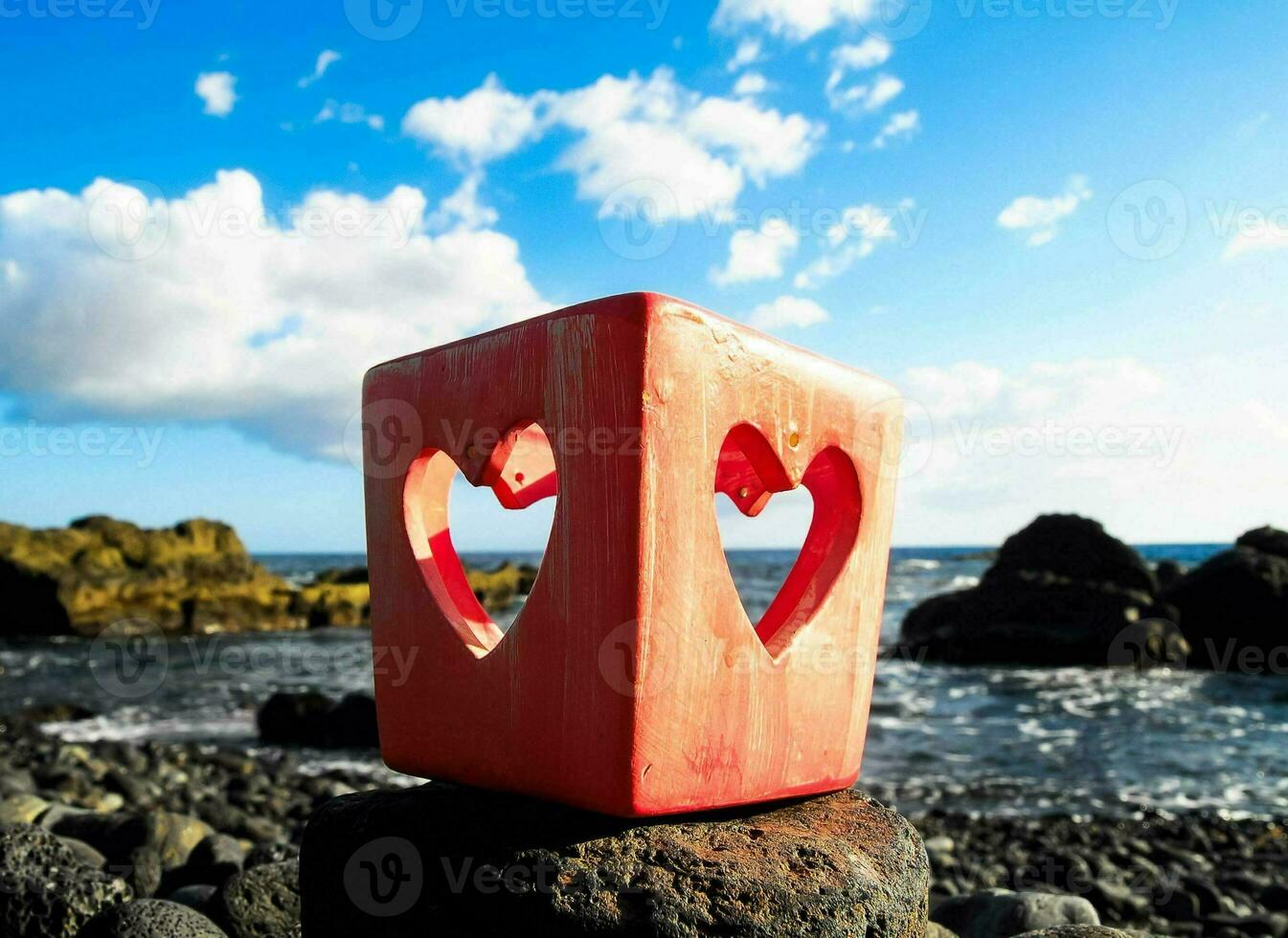 un' rosso cubo con Due cuori su esso seduta su un' roccia foto