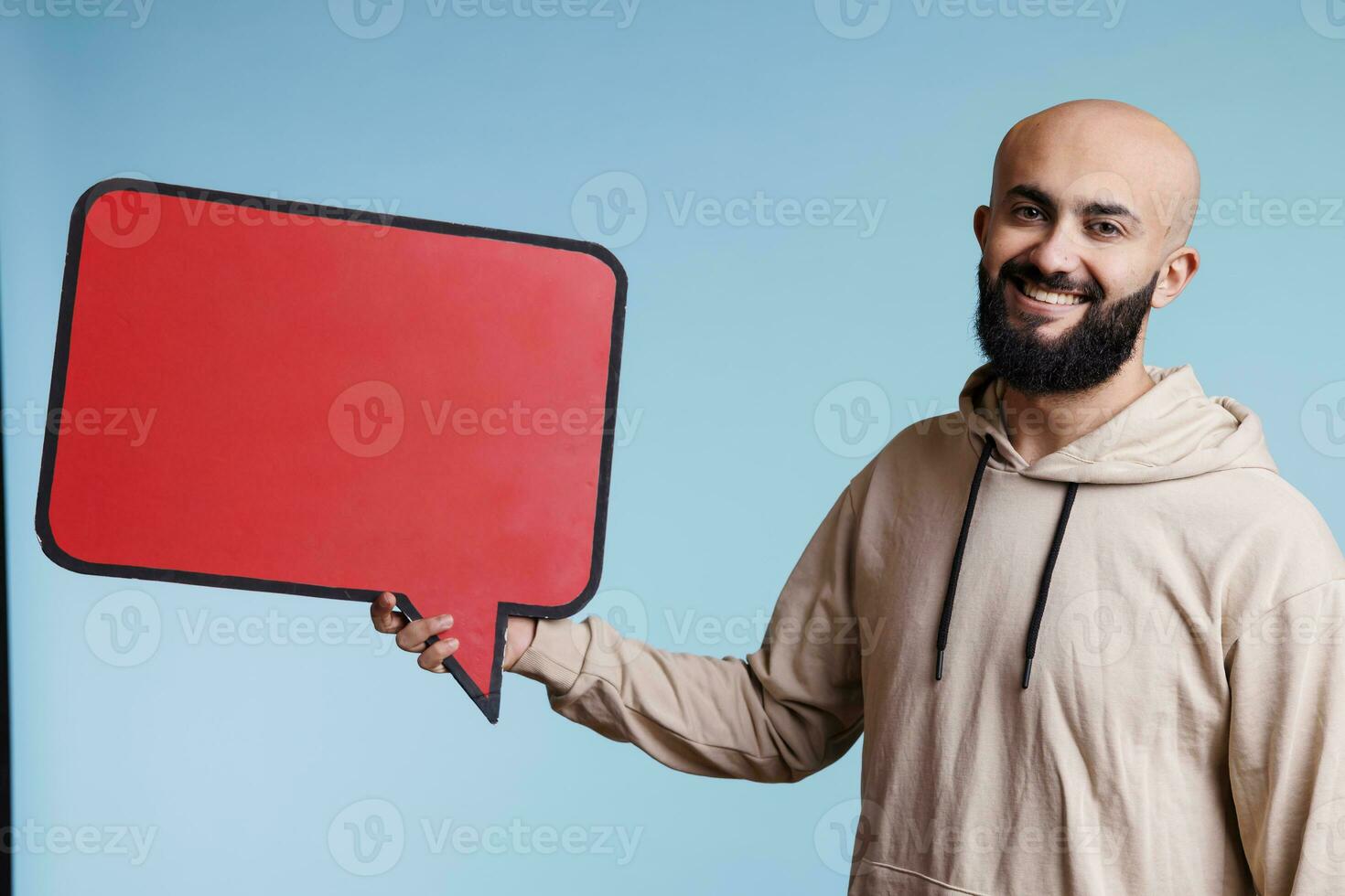 sorridente arabo uomo Tenere discorso bolla per Prodotto pubblicità finto su ritratto. allegro giovane persona in posa con parlare Palloncino con copia spazio finto su e guardare a telecamera foto