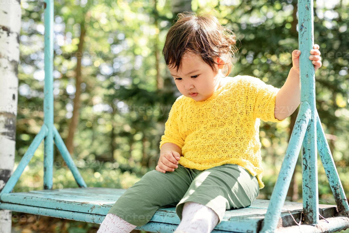 triste bambina seduta sull'altalena foto