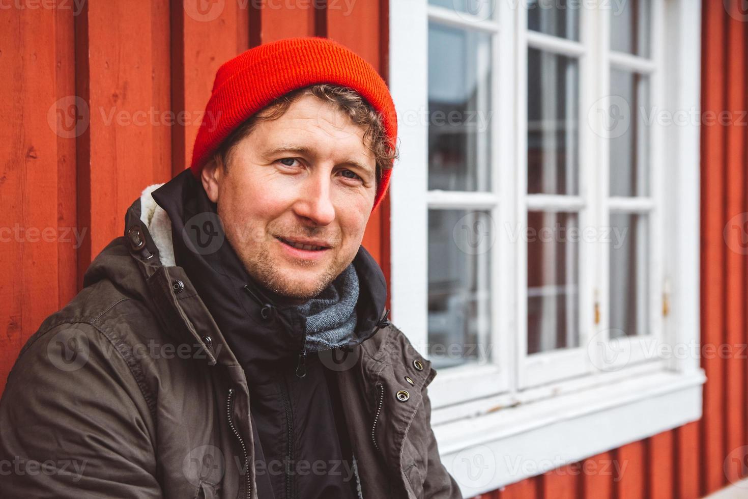 l'uomo del viaggiatore ritratto si siede vicino alla casa di legno di colore rosso foto