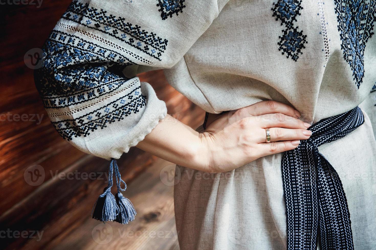 dettagli della camicia ricamata della sposa sullo sfondo di una casa in legno foto