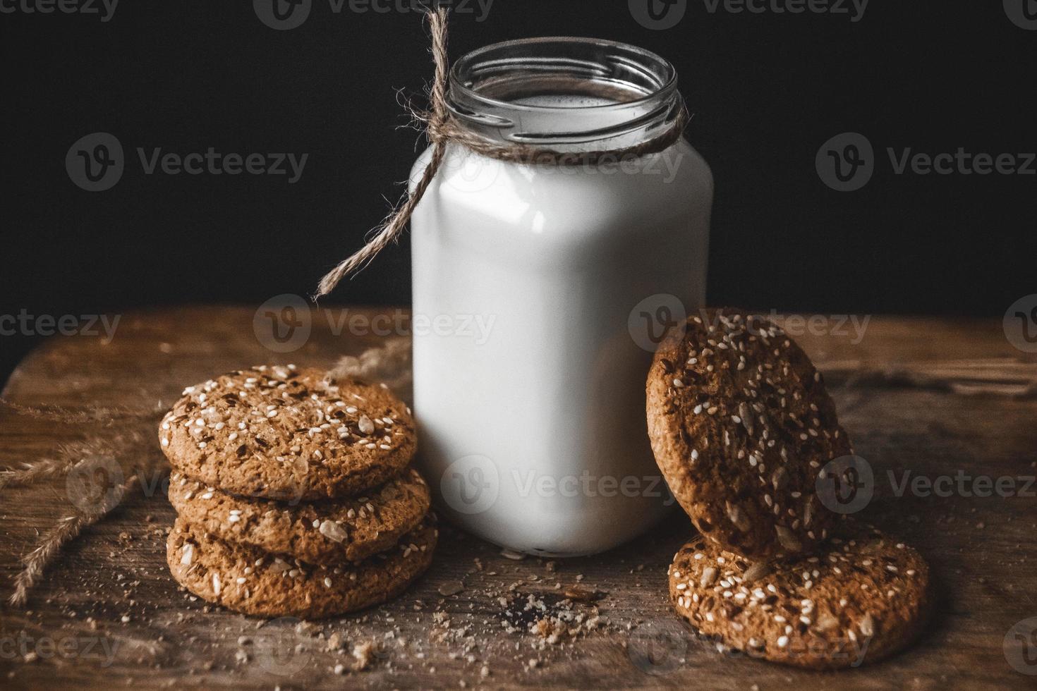 biscotti ai cereali con una brocca di latte su uno sfondo di legno. foto