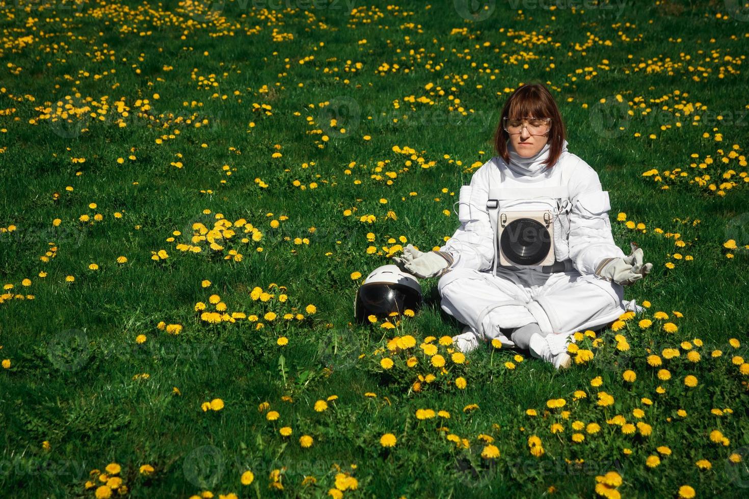 donna astronauta senza casco si siede su un prato verde tra i fiori foto