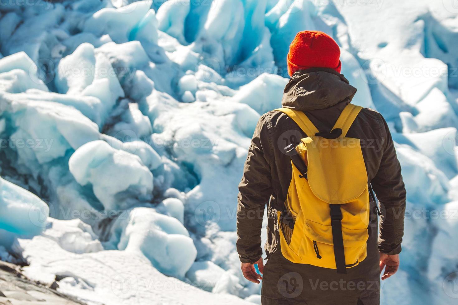 uomo viaggiatore in piedi su una roccia sullo sfondo di un ghiacciaio foto