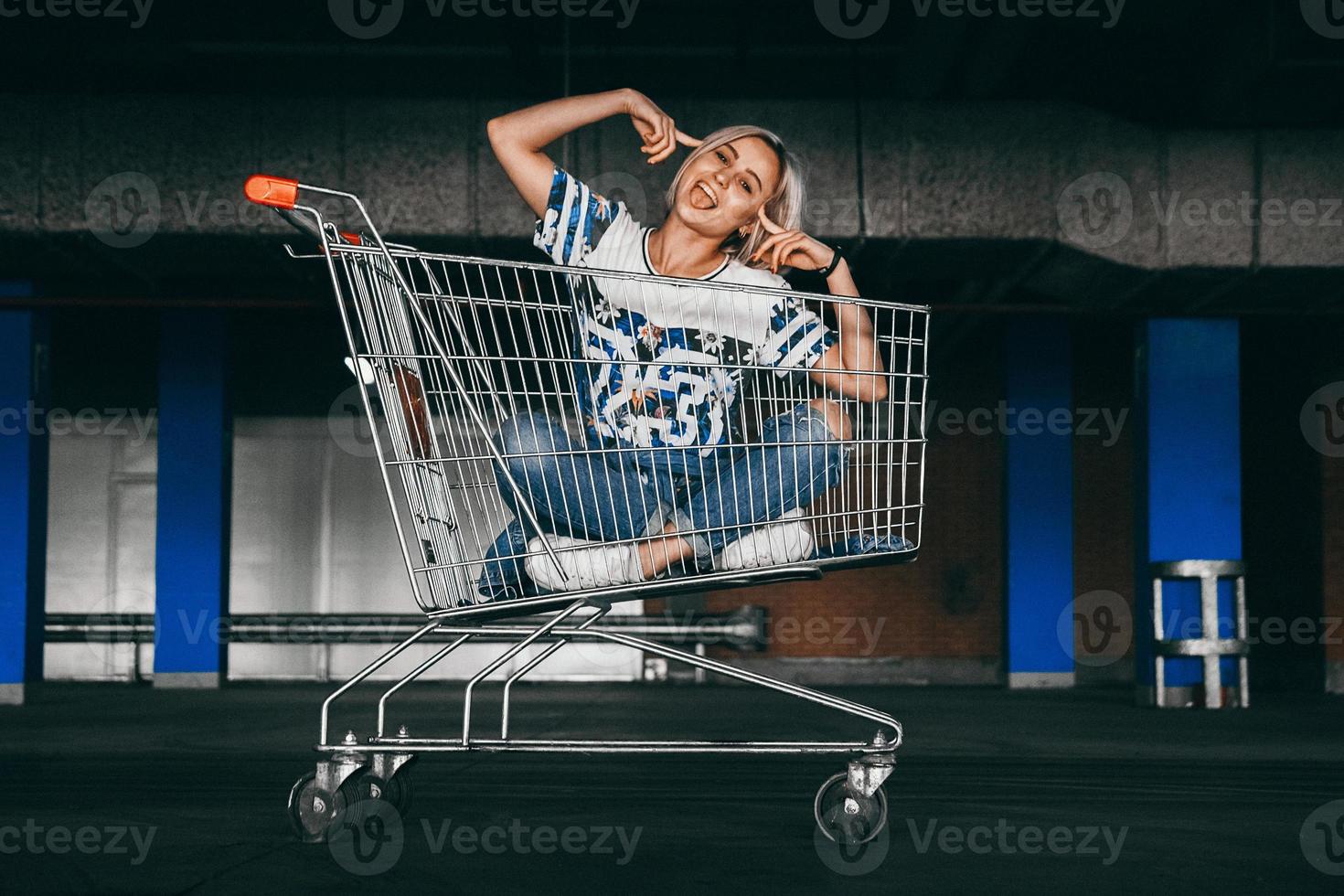 donna vestita in jeans con carrelli della spesa nel parcheggio foto