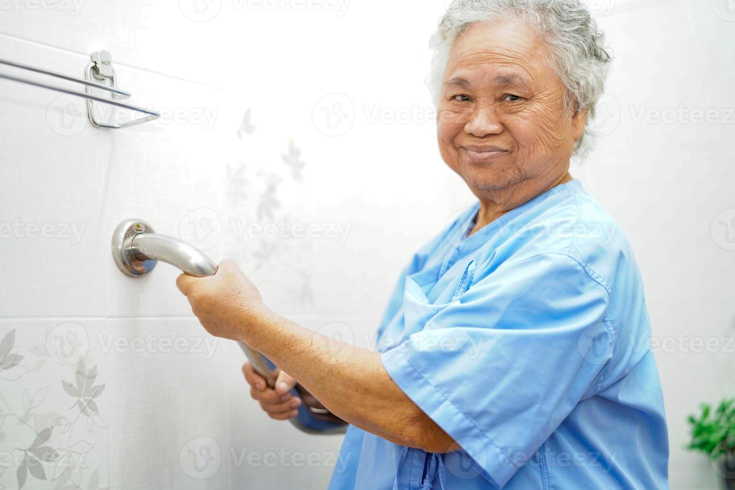 donna anziana asiatica paziente usa la sicurezza della maniglia del bagno della toilette foto