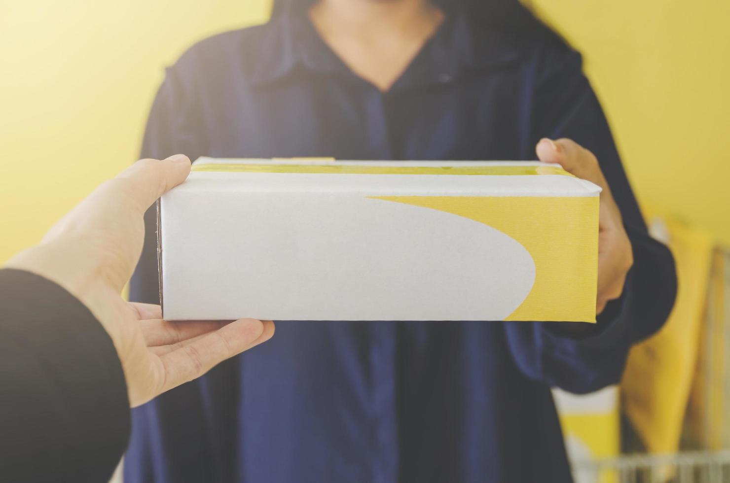 una mano umana che tiene un pacco e una cassetta delle lettere per la consegna e la spedizione. foto