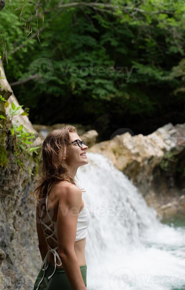 giovane donna felice che si gode la cascata foto