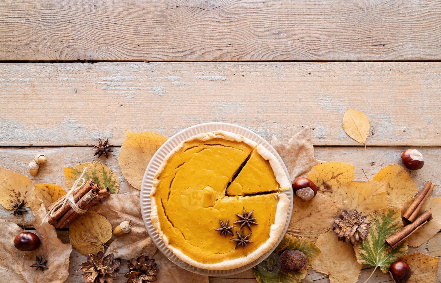 torta di zucca fatta in casa con foglie autunnali su fondo rustico, vista dall'alto foto