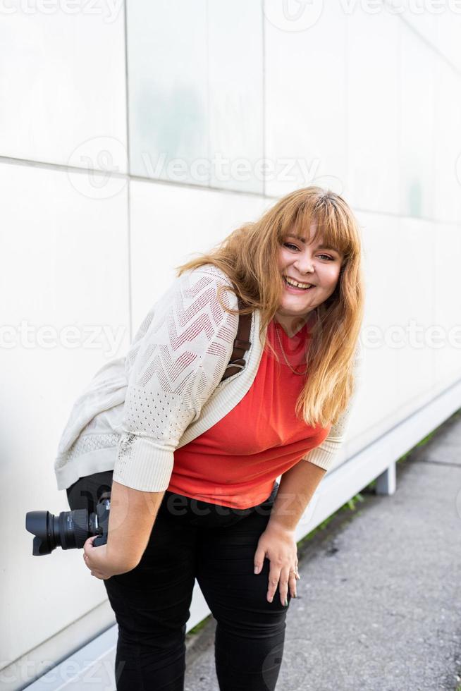 ritratto di donna sovrappeso che scatta foto con una macchina fotografica all'aperto